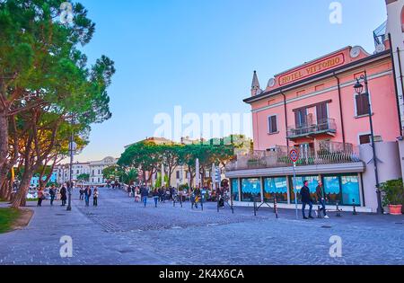 DESENZANO DEL GARDA, ITALIE - 10 AVRIL 2022 : la soirée via Porto Vecchio avec maisons historiques et grands pins, sur 10 avril à Desenzano del Garda Banque D'Images