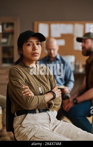 Jeune femme hispanique déprimée avec étiquette de chien militaire sur la chaîne de balle accrochée sur son cou regardant la caméra pendant la session psychologique Banque D'Images