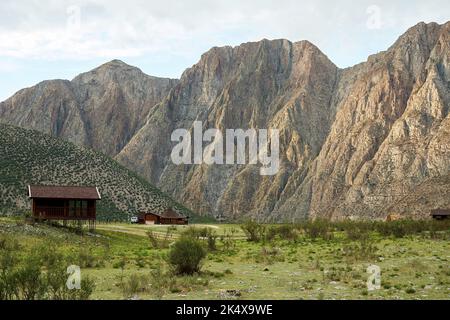 Petites maisons en bois dans la vallée avec des montagnes à l'arrière. Coucher de soleil sur la colline Banque D'Images