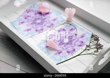 Terrasse avec cartes d'ange maison sur plateau blanc à la table de la maison, entouré de pierres semi-précieuses cristaux de quartz rose et figurine en forme d'ange. Banque D'Images