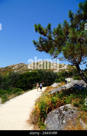 Touristes randonnée sur le sentier jusqu'au sommet de l'Illa de Faro ou Montefaro, Iles du Cies, Galice, Espagne Banque D'Images