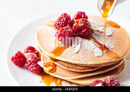 Pile de crêpes à la framboise, aux amandes et au sirop d'érable sur une assiette blanche, gros plan. Petit déjeuner. Banque D'Images