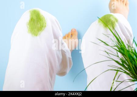 Taches d'herbe sales sur les vêtements.sur un fond bleu. Taches vertes sur les genoux du pantalon. Vêtements abîmés. Isolé. Banque D'Images