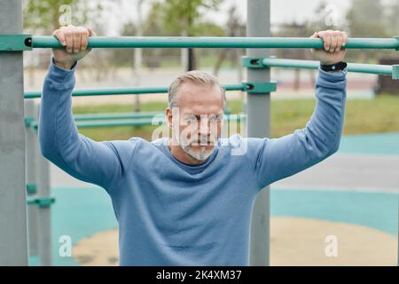 Portrait d'un beau homme mature travaillant à l'extérieur et regardant loin avec motivation dans un cadre urbain minimal Banque D'Images