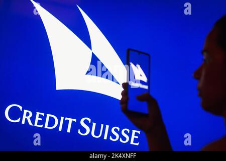 Dans cette illustration, le logo de la banque suisse Credit Suisse Group est visible sur le fond d'une femme silhouetée tenant un smartphone. Banque D'Images