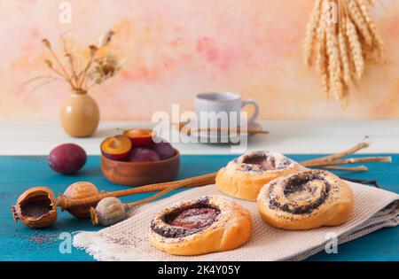 Gros plan de mini-tartes farcies de graines de pavot moulues avec des prunes fraîches sur une table en bois bleu, angle de vue bas, pas de personnes. Banque D'Images