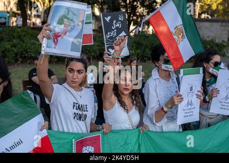 Barcelone, Espagne. 04th octobre 2022. Les manifestants tiennent des pancartes et le drapeau iranien pendant la manifestation. Une centaine de personnes se sont rassemblées sur la Plaza de Catalunya en solidarité avec les femmes qui souffrent de la répression de la dictature islamique en Iran après le meurtre de Masha Amini aux mains de la "police orale" pour ne pas porter correctement le voile obligatoire. Crédit : SOPA Images Limited/Alamy Live News Banque D'Images