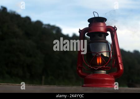 Ancienne lanterne classique à l'huile. Gros plan de lanterne rouge sur ciel bleu sur le fond de la forêt. Banque D'Images