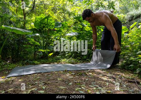 Jeune latin qui organise son tapis de yoga, à l'intérieur d'une forêt sur une plaine, contact direct avec la nature, mexique Banque D'Images