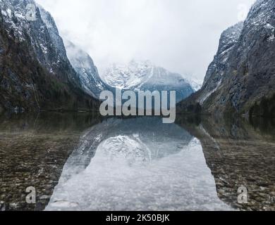 Vue panoramique sur les montagnes qui se réfléchit sur le lac Obersee en Allemagne par une journée de brouillard Banque D'Images