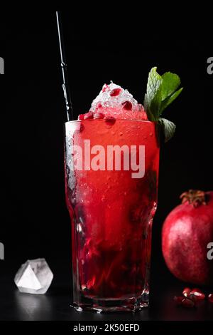 Verre de jus de grenade avec glace et menthe, sur fond noir Banque D'Images