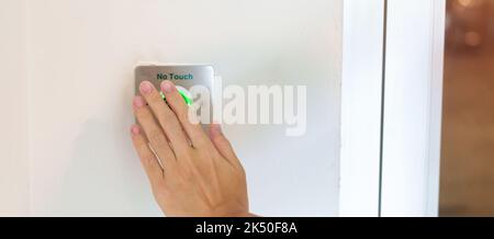 Ouvrez la porte à la main en appuyant sur le bouton du capteur sans contact situé sur le mur du bureau ou de l'appartement. Sans contact, moderne, concept de technologie et de sécurité Banque D'Images