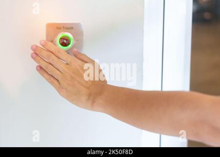 Ouvrez la porte à la main en appuyant sur le bouton du capteur sans contact situé sur le mur du bureau ou de l'appartement. Sans contact, moderne, concept de technologie et de sécurité Banque D'Images