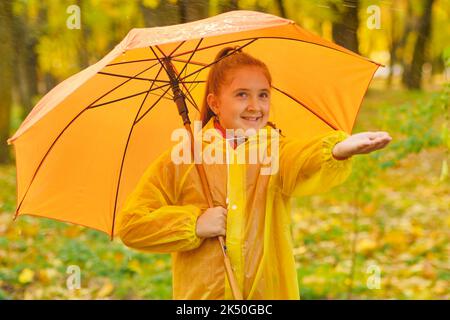 Un enfant heureux qui attrape des gouttes de pluie dans le parc d'automne Banque D'Images