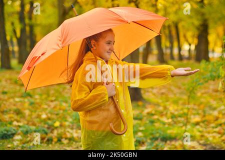 Un enfant heureux qui attrape des gouttes de pluie dans le parc d'automne Banque D'Images