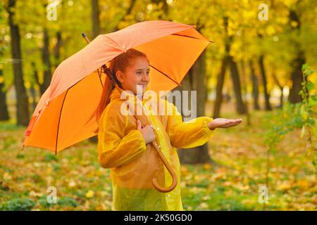 Un enfant heureux qui attrape des gouttes de pluie dans le parc d'automne Banque D'Images