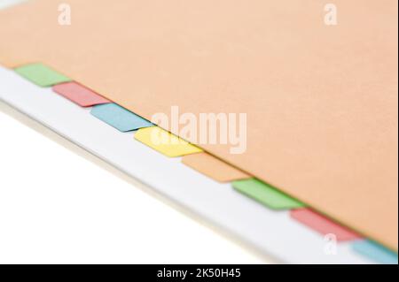 Vue rapprochée de quelques onglets d'index colorés alignés dans un dossier manille sur un fond blanc Banque D'Images