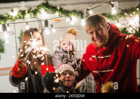 Une grande famille heureuse fête noël dans la nature et accueille des amateurs de sparkers.Les parents avec trois fils voyagent dans une maison mobile. Banque D'Images