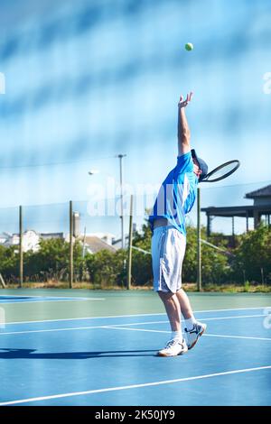 Il s'agit d'un ace. Un joueur de tennis masculin lance le ballon dans l'air pour un service - tennis. Banque D'Images