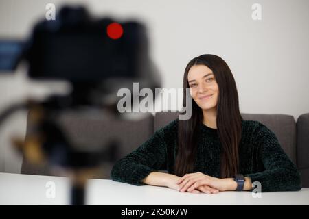 Heureux blogueur parlant sur caméra vidéo. Femme blanche et gaie filmant un film vidéo à la maison Banque D'Images