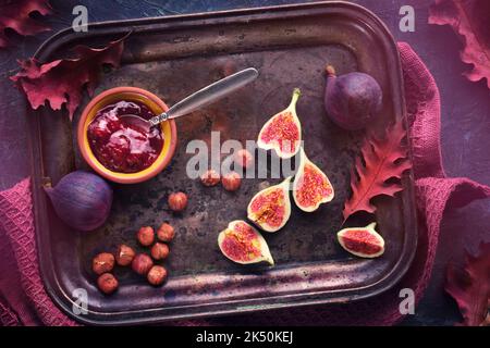 Arrière-plan de durée automatique. Fruits frais coupés en deux sur un ancien plateau métallique vintage serviette magenta sur un plateau texturé gris foncé. Banque D'Images