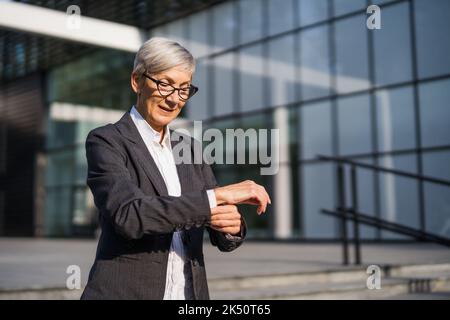 Portrait extérieur d'une femme d'affaires senior réussie devant le bâtiment de l'entreprise. Banque D'Images