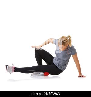 Déploiement de ses cuisses. Une jeune femme s'entraîner à l'aide d'une balle d'exercice. Banque D'Images