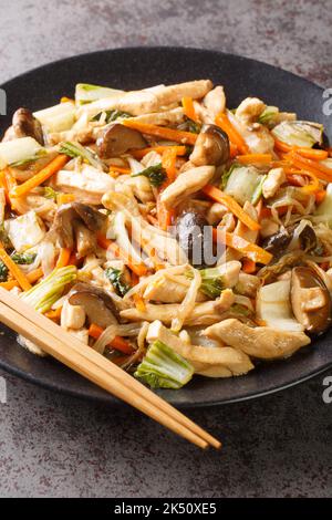 Hachez le poulet sauté Suey avec les légumes en gros plan dans une assiette sur la table. Verticale Banque D'Images