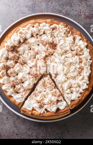 Morceau Rijstevlaai Dutch Rice Pudding Tart avec de la crème fouettée et des copeaux de chocolat dans une assiette sur la table. Vue verticale du dessus Banque D'Images