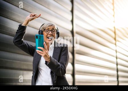 Portrait en plein air d'une femme d'affaires chevronné qui écoute de la musique en pause au travail. Banque D'Images