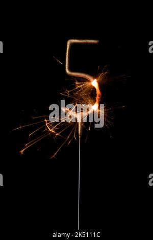 Feu de sparkler doré en forme de cinq, chiffre 5, isolé sur fond noir Banque D'Images