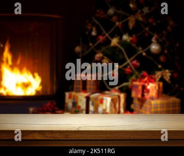 Table en bois vide sur fond de Noël défoqué avec arbre de Noël, cadeaux et cheminée ; espace libre pour votre décoration. Banque D'Images