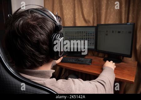 homme dans un casque travaillant à un ordinateur, indépendant à la maison. Banque D'Images