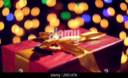 cadeaux magnifiquement emballés avec des rubans roses. cadeaux sur des lumières de bokeh ou arrière-plan lumineux des guirlandes. gros plan, rotation. Noël ou nouvel an. Concept caritatif. Ambiance festive. Photo de haute qualité Banque D'Images