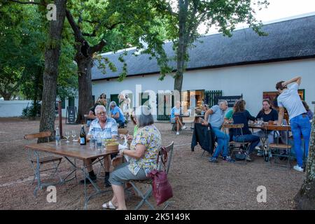 Visiteurs buvant à des tables de plein air au marché nocturne de Boschendal à Western Cape, Afrique du Sud Banque D'Images