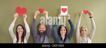 Groupe de jeunes et de personnes âgées heureux souriant et tenant des valentines en forme de cœur rouge Banque D'Images