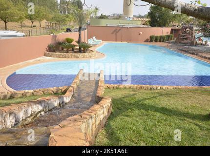 Resort. Piscine de luxe avec chute d'eau et chaises longues le jour d'un ciel bleu clair. Cascade d'eau chaude faite de pierres par l'homme. Vue de dessus. Panoramique. w Banque D'Images