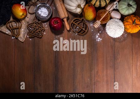 Plat de cuisson d'automne posez avec des ingrédients de tarte, des emporte-pièces en forme de feuille, de citrouille, des symboles d'automne, des citrouilles et des pommes sur un woo sombre et confortable Banque D'Images