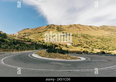 Paysage de la chaussée sinueuse d'asphalte traversant la vallée sous un ciel bleu nuageux dans les montagnes des Pyrénées à Lleida Banque D'Images