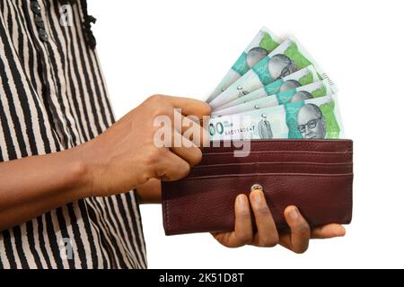 Main féminine juste tenant un sac à main brun avec des notes de peso colombiennes, main enlevant l'argent du sac à main isolé sur fond blanc Banque D'Images