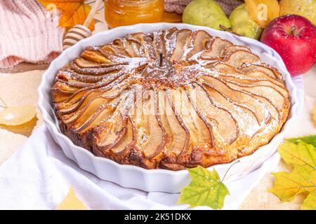 Tarte aux poires maison, gâteau éponge avec poire en tranches, cannelle et miel, avec poires fraîches sur fond de pierre beige vue du dessus espace copie Banque D'Images