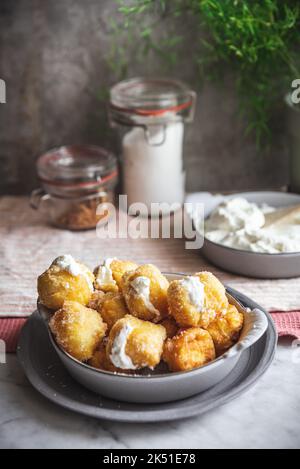 Bol avec des petites bouchées de nonne croquantes farcies de fromage à la crème placées sur la table dans la cuisine à la maison Banque D'Images