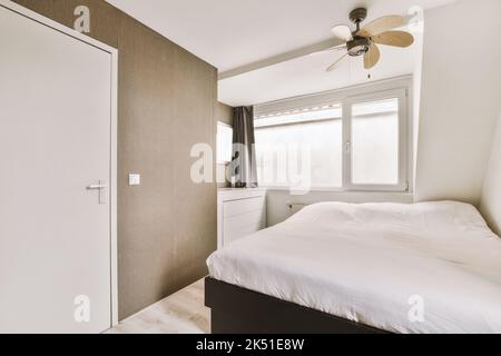 Lit confortable avec couette et oreiller près de l'armoire dans la chambre lumineuse de la maison Banque D'Images