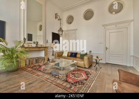 Canapé confortable avec coussins moelleux et tapis ornemental de style oriental dans le salon spacieux avec parquet et divers éléments décoratifs i Banque D'Images