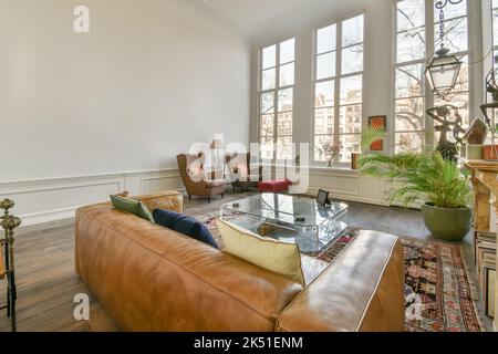 Canapé confortable avec coussins moelleux et tapis ornemental de style oriental dans le salon spacieux avec parquet et divers éléments décoratifs i Banque D'Images