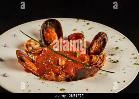 Des spaghetti de fruits de mer de plus près avec sauce tomate servis sur une assiette sur fond noir au restaurant Banque D'Images