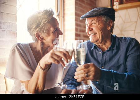 Couple de personnes âgées avec toast au champagne au restaurant pour anniversaire de mariage. Homme et femme senior avec boisson alcoolisée célébrant l'amour, la famille et Banque D'Images