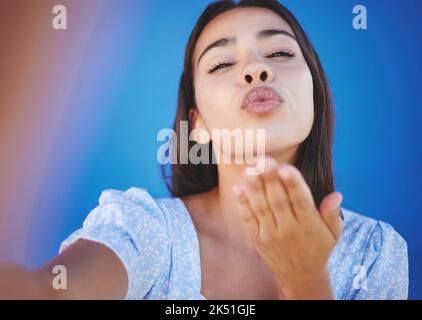 Baiser soufflant, selfie et jeune femme lors de vacances d'été debout sur fond bleu. Lèvres, beauté et portrait d'une belle fille du Mexique Banque D'Images