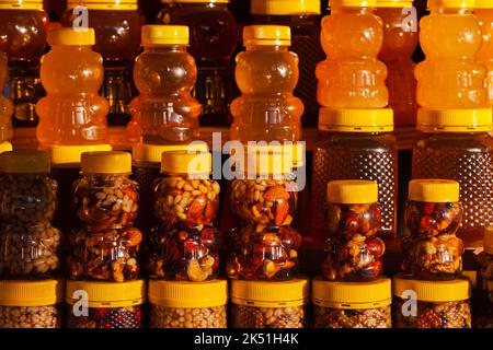 Assortiment de miel avec noix dans des pots en plastique en forme d'ours se tiennent sur une fenêtre d'atelier dans une rangée. Gros plan avec mise au point douce sélective Banque D'Images