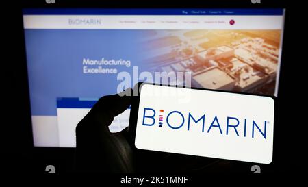 Personne tenant un téléphone portable avec le logo de la société américaine BioMarin Pharmaceutical Inc. À l'écran en face de la page Web d'affaires. Mise au point sur l'affichage du téléphone. Banque D'Images